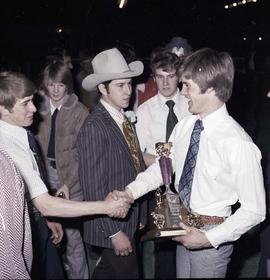 Man holding a trophy is congratulated by other men at the 1977 Little International Agricultural Exposition at South Dakota State University.