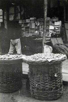 Large baskets of fruit for sale at a bazaar in Fushun, Manchuria in northern China; written in pencil on the back: Fruit bazaar at Futachien 1924.