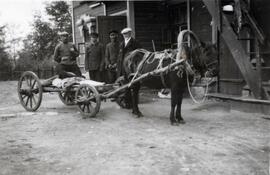 N.E. Hansen and his three assistants stand by a horse-drawn wagon by a building at Mendoche before they begin a search for hardy peach trees in northern China; written in pencil on the back: Mendoche 1924 North China.