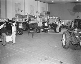People looking at a display of tractors at the machine show during the 1958 Little International Exposition at South Dakota State College.