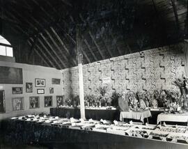 N.E. Hansen standing by a small table in a room with horticultural displays of flowers and fruits.