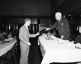 Man handing a plaque to another man during a banquet at the 1949 Little International Exposition at South Dakota State College.