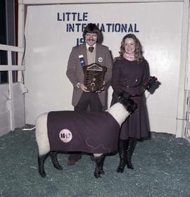 Man and woman are holding trophies standing by a sheep at the 1975 Little International Agricultural Exposition at South Dakota State University