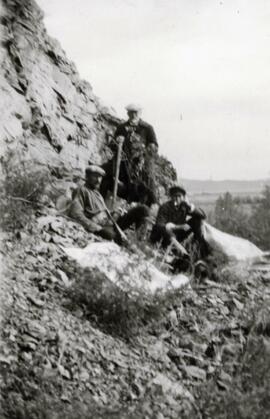 N.E. Hansen and two assistants climb rough terrain to gather specimens in their search for hardy peach trees in Mendoche in northern China in 1924; written in pencil on the back: Mendoche, North China 1924.