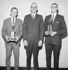 Three men, two of which are holding trophies, at the 1967 Little International Agricultural Exposition at South Dakota State University.