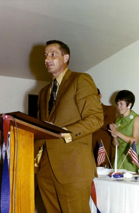 Richard Kneip speaking during his 1970 campaign. A woman in a green dress standing in the background.