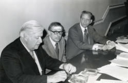 Senator Tip O'Neill and Congressman Frank Denholm during a press conference, a man with a bandage on his forehead it sitting between them