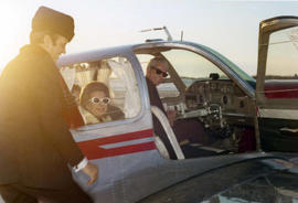Frank Denholm boarding an airplane. Millie Denholm and the pilot are seated inside the airplane.