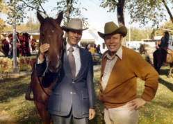Frank Denholm and a man standing outside. Denholm is standing next to a horse.