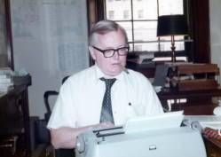Staff member with a cigar in his mouth typing on a typewriter in Frank Denholm's Washington, D.C. office.