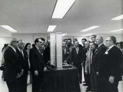 Congressman Frank Denholm (center to the right of the towers in a light color jacket) with a large group of people looking at a model of the World Trade Center building