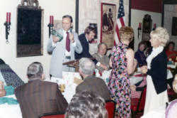 Frank Denholm is holding a glass jar while standing at the podium at a Democratic Party campaign event.