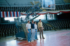 South Dakota basketball players wearing casual clothing and USA polo shirts pose in front of hoop in basketball stadium in Cuba