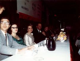 Frank and Millie Denholm at an International Association of Machinists event. They are seated at a long table with other people.