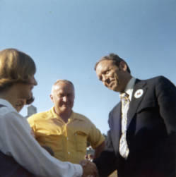 Frank Denholm standing outside by a building with two constituents.
