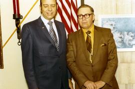 Frank Denholm standing next to a man at an event. Denholm has his eyes closed.