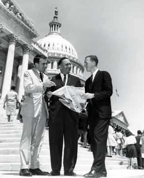 Representative Ben Reifel, James Brown, and James Hunt looking at a newspaper of the US Capitol steps