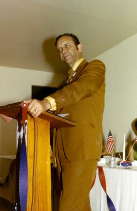 Frank Denholm standing at a podium during a campaign event.