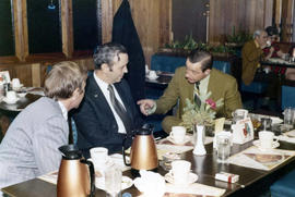 Frank Denholm and Richard Kneip are having a discussion in a restaurant with another man.