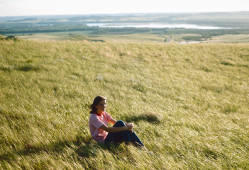 Janet Johnson sitting in the grass on Blossom Butte north of Bismarck, North Dakota on the east side of the Missouri River.