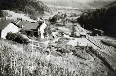 Valley of the Da Hinggan mountain range in northern China where the Trans-Siberian Railway runs, there are buildings in the foreground; written in pencil on the back: In Hinggan North China in mountains 1924.