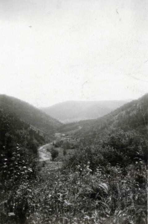 View of a river in a valley of the Da Hinggan mountain range in northern China; written in pencil on the back: In Hinggan North China mountains 1924.