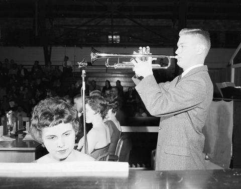 Man playing a trumpet while a woman accompanies him on a piano on the stage at the 1960 Little International Exposition at South Dakota State College.