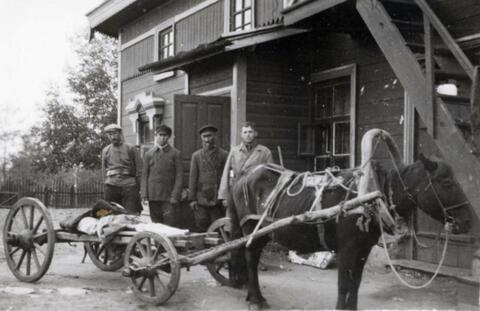 Four of N.E. Hansen's assistants stand by a horse-drawn wagon by a building at Mendoche before they begin a search for hardy peach trees in northern China; written in pencil on the back: Mendoche 1924 North China.