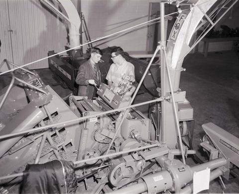 Vendor speaks with a man about the farm equipment they are standing by in the machinery show at the 1970 Little International exposition at South Dakota State University.