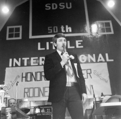 Man speaking into a microphone at the 1973 Little International Agricultural Exposition at South Dakota State University.