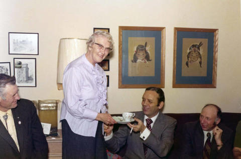 Frank Denholm being served a cup of coffee by a woman.