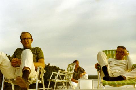 Frank Denholm (right) with two other men relaxing on house boat on a lake.