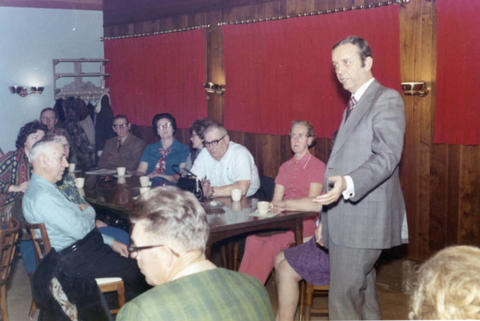 Frank Denholm speaking to a group in a café.