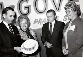 Frank Denholm is holding a McGovern campaign hat while Evelyn Lord, Bob Chamberlain, Donna Kuhfeld look at it at a campaign event in Aberdeen, South Dakota.
