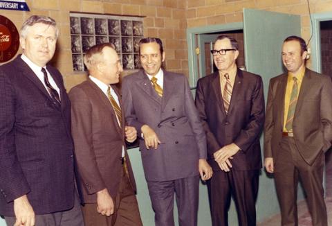 Frank Denholm talking with other men at an event.