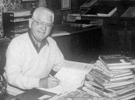 Black-and-white photograph of Bob Karolevitz working at his desk.