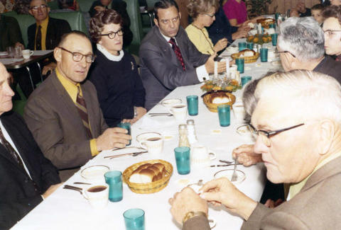 Frank Denholm seated at a table visiting with constituents at an event.