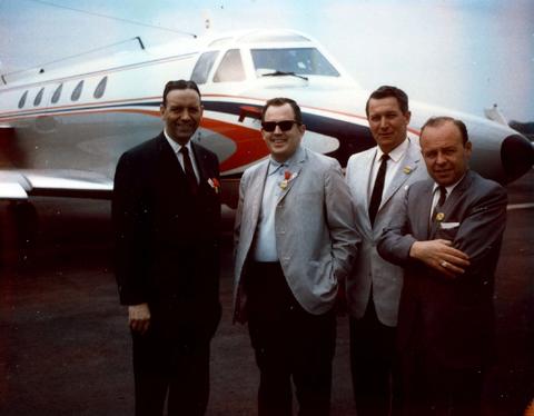 Frank Denholm is with constituents on the tarmac of an airport. They are standing in front of an airplane.