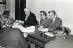 Senator Tip O'Neill and Congressman Frank Denholm during a press conference, a man with a bandage on his forehead it sitting between them